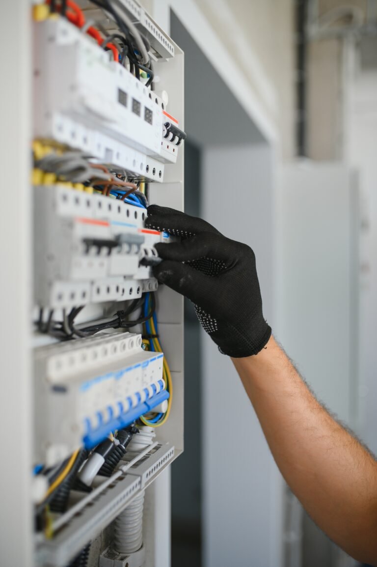 A male electrician works in a switchboard